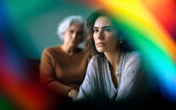 A serious-looking younger woman sits in the foreground with an older woman behind her, both partially obscured by colorful, blurred rainbow light effects.