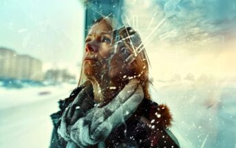 A woman wearing a scarf and coat looks up thoughtfully in a snowy environment. Her double-exposed face, overlayed with floating clock numerals and shards, creates a surreal, dreamlike effect with a hint of passing time.