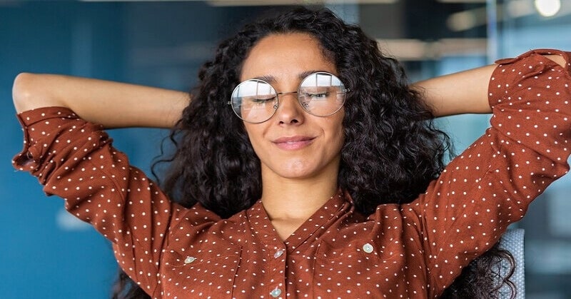 young woman with hands behind her head and eyes closed - illustrating a highly intuitive person