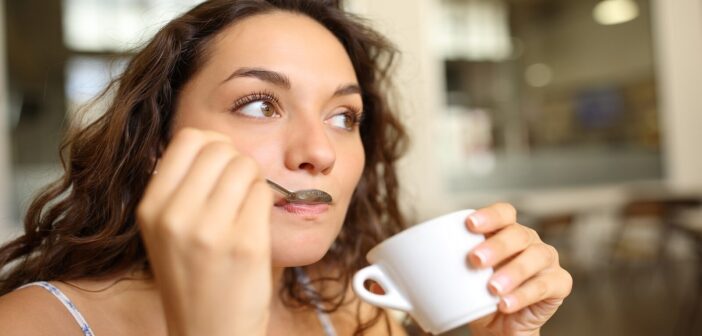 young woman drinking coffee with a spoon