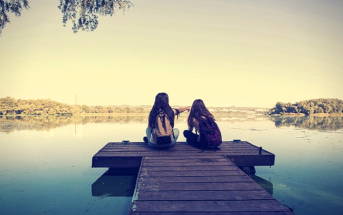 two girls sitting on pier