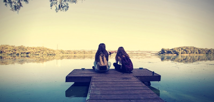 two girls sitting on pier
