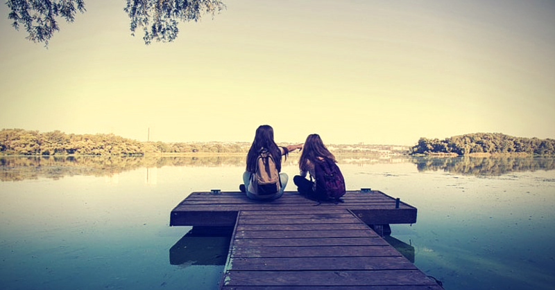 two girls sitting on pier