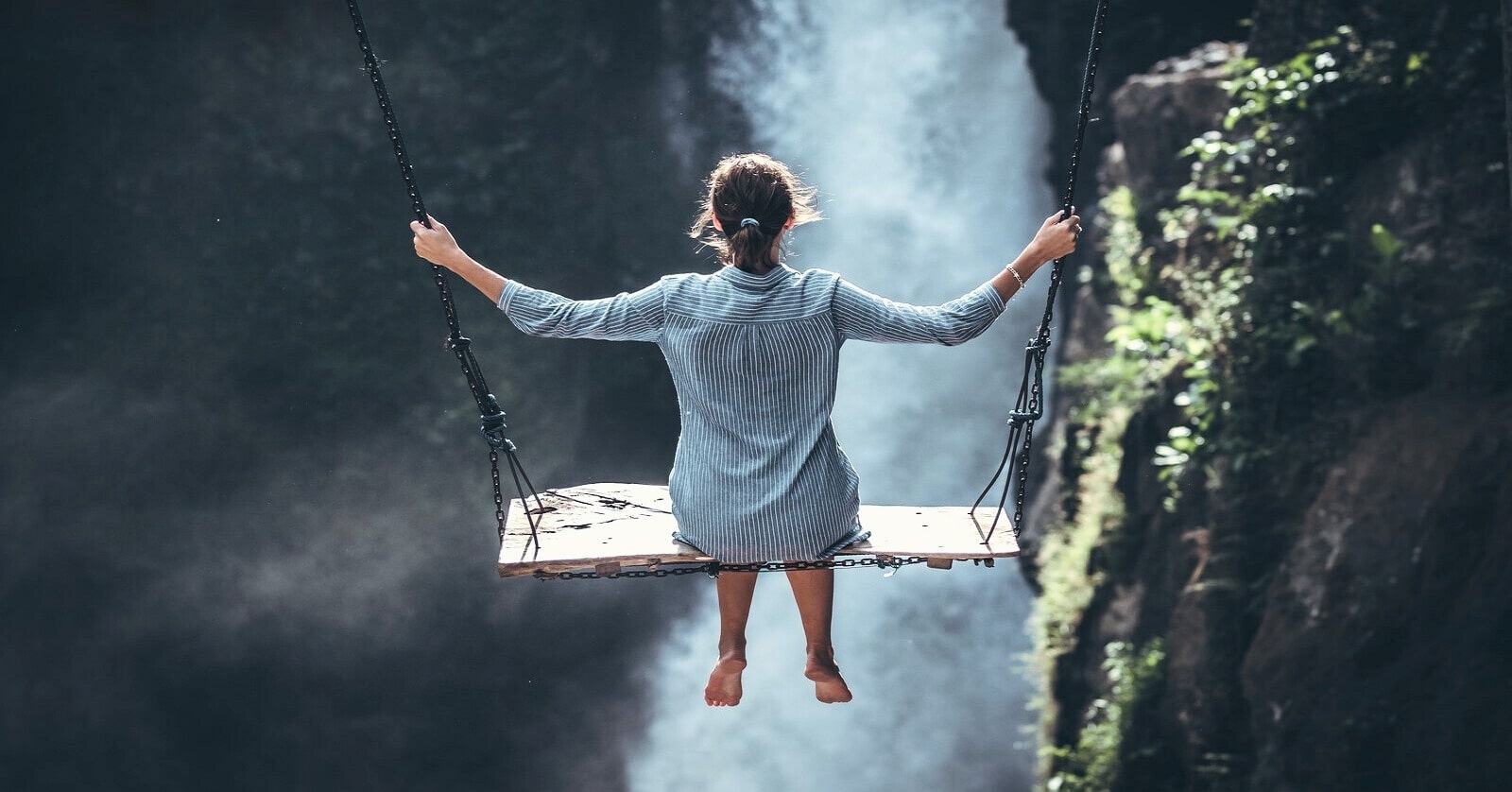 woman on large swing with waterfall in the background