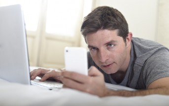 man checking phone and laptop