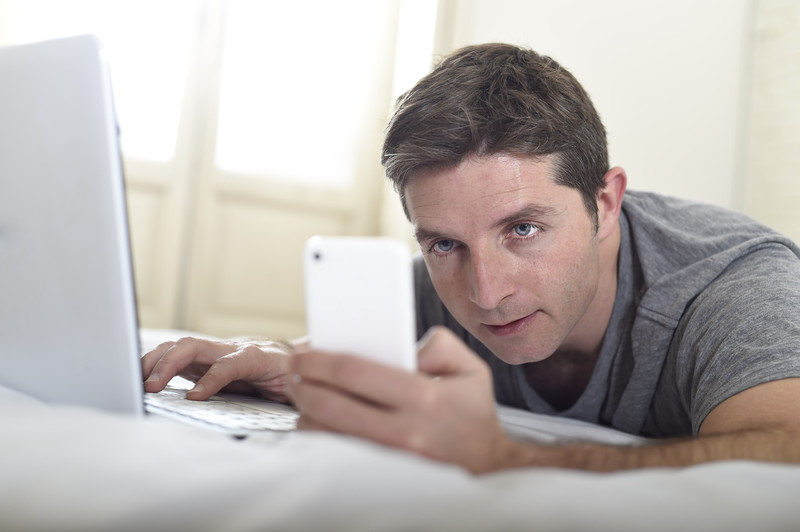 man checking phone and laptop