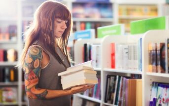 a young brunette woman in a bookshop carrying a selection of self-improvement books