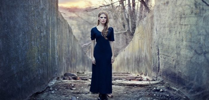 woman in dark dress between grey walls