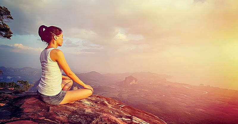 woman meditating on mountain - concept of inner peace