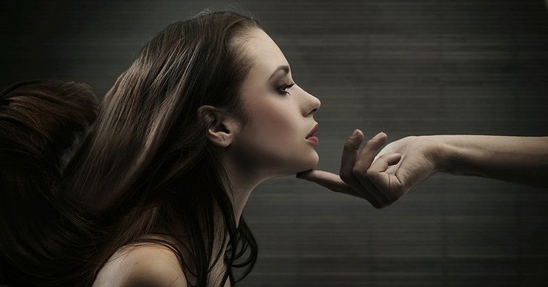 hand holding woman's head - concept of narcissistic superiority