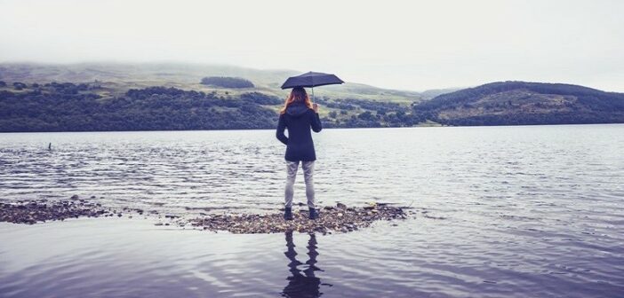 woman with umbrella at lake - concept being humble