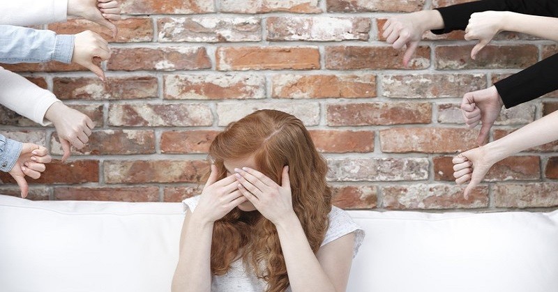 ashamed woman surrounded by thumbs down