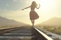 woman walking on railway track in sun