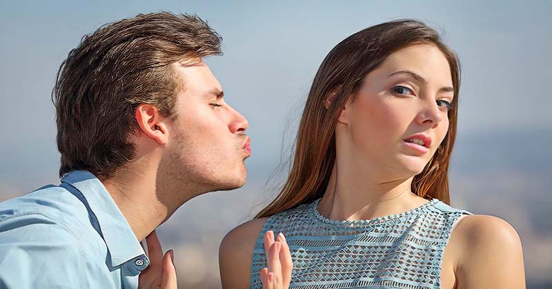 woman avoiding kiss from man - concept of unrequited love