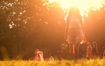 woman walking barefoot with sun in background - concept of free spirit