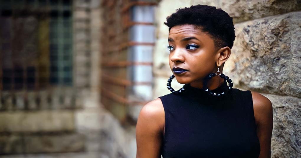 woman looking serious against brick wall, representing an Alpha female