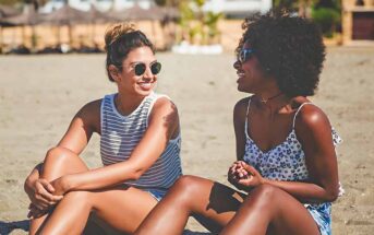 two young friends sitting on beach talking