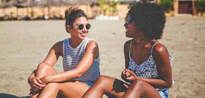 two young friends sitting on beach talking