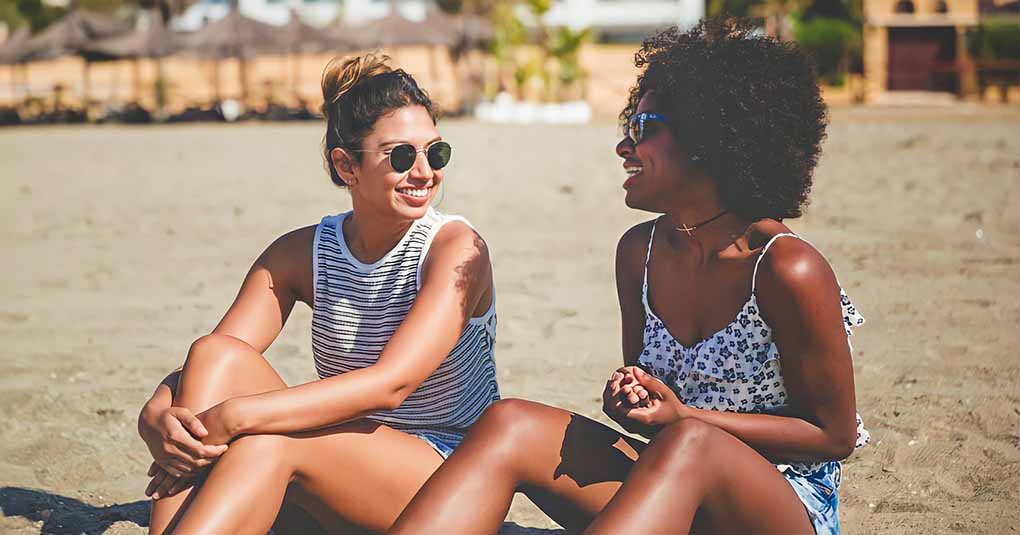 two young friends sitting on beach talking