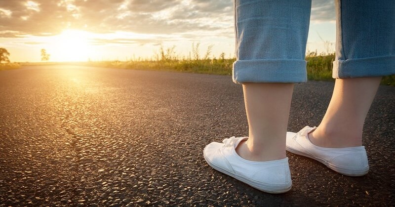 woman's feet on path towards sun