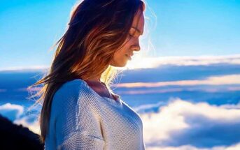 young woman looking down with clouds in background - concept of spiritual maturity