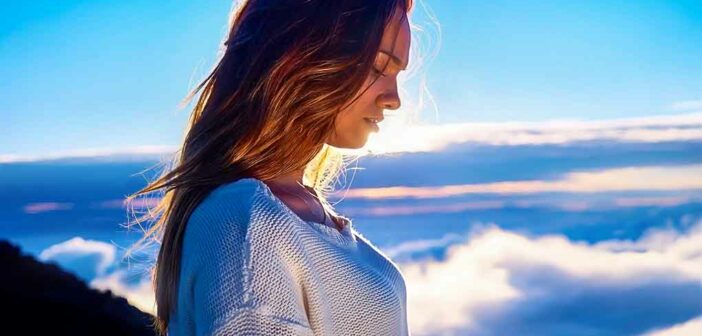 young woman looking down with clouds in background - concept of spiritual maturity