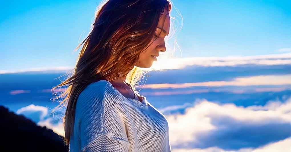 young woman looking down with clouds in background - concept of spiritual maturity