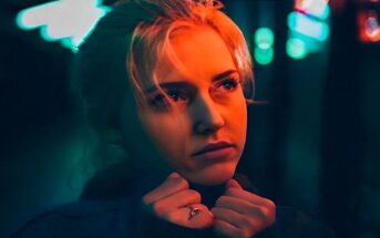 young woman looking anxious under red street light