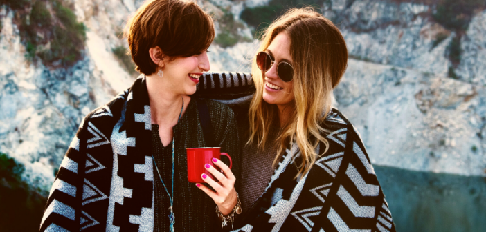 good friends sharing blanket and hot drink