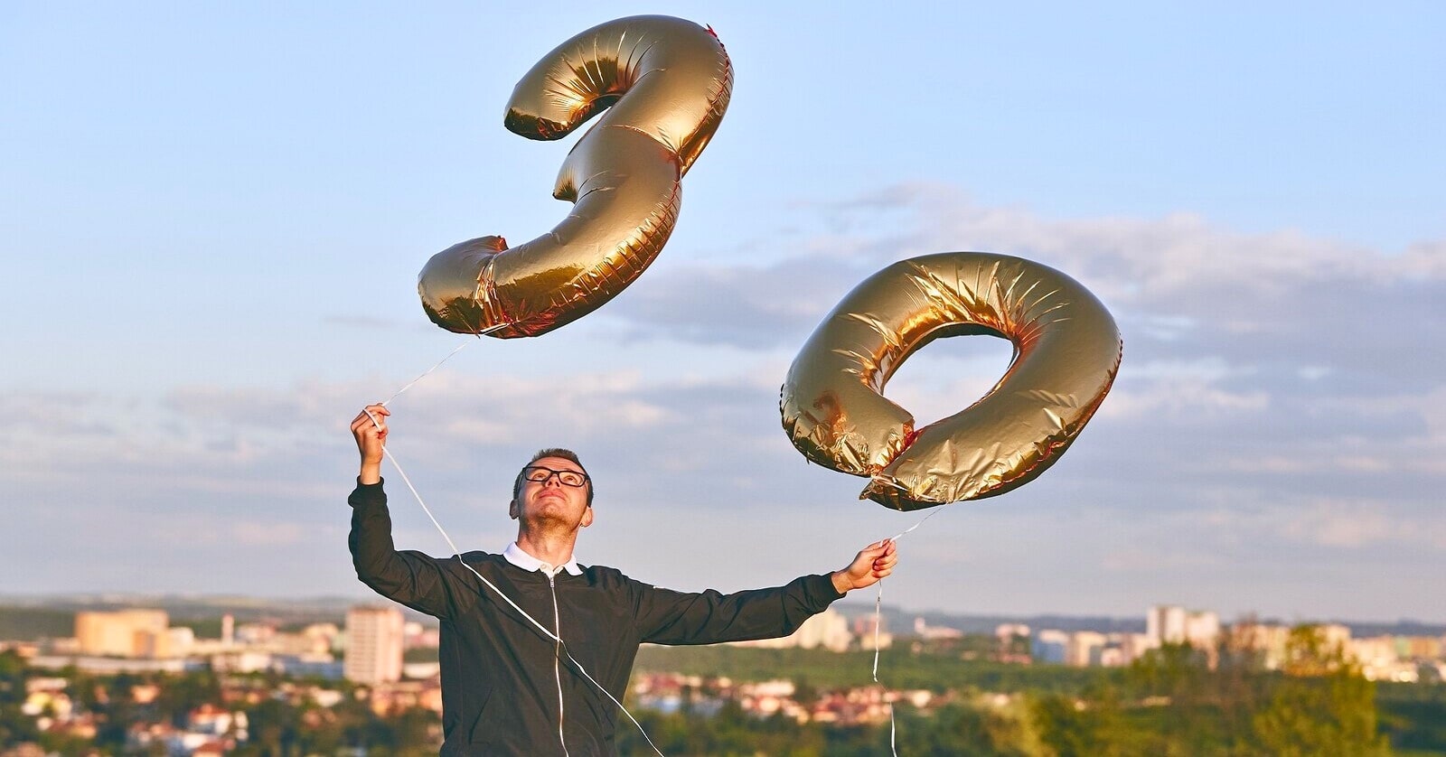 man holding a 30 balloon for his birthday