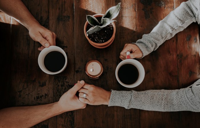 couple holding hands across coffee table