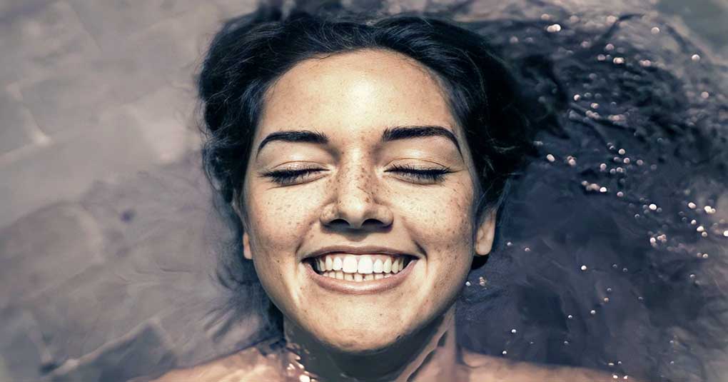 young woman lying in water smiling