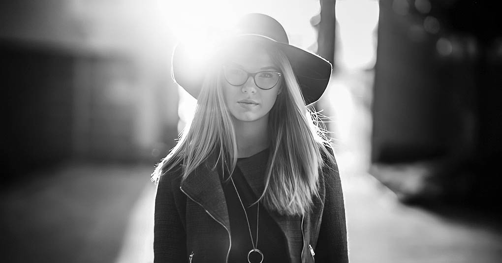 black and white photo of woman in hat on sunny street