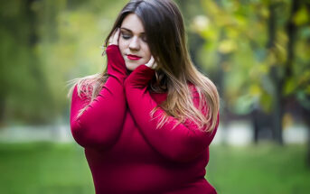 curvy young empath woman in red sweater holding head