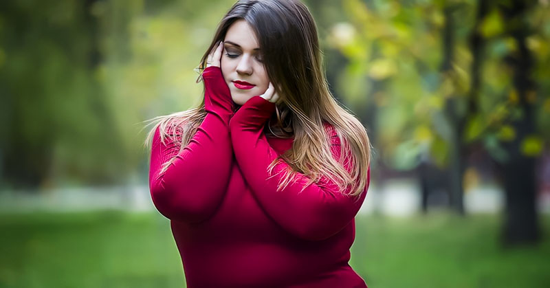 curvy young empath woman in red sweater holding head