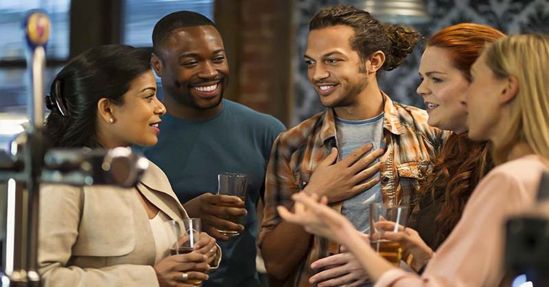 group of men and women talking at a bar