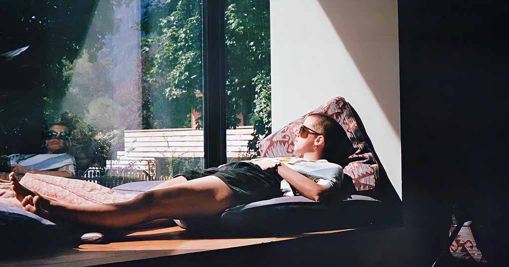 woman relaxing on window ledge in sun