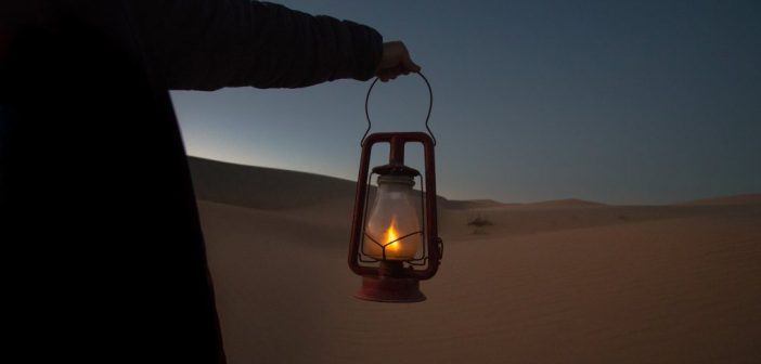man holding lantern in desert