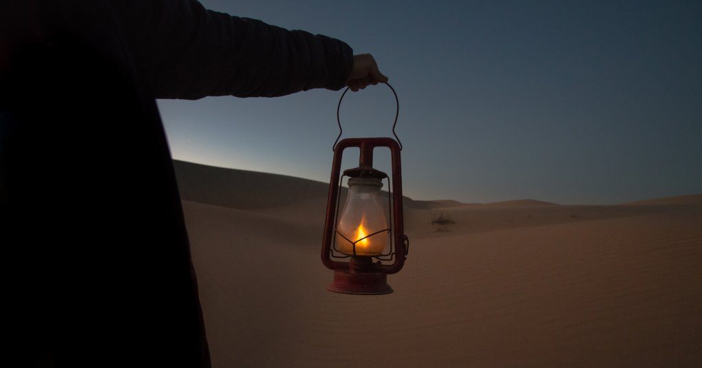 man holding lantern in desert