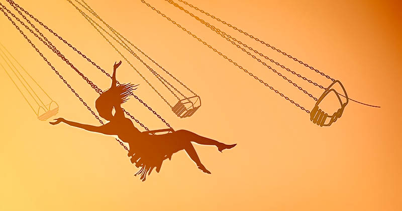 silhouette of young woman on swing against orange sky, showing her inner child