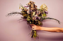 outstretched hand with bouquet of dying flowers
