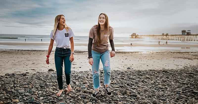 two young women walking up a beach - concept of accepting others