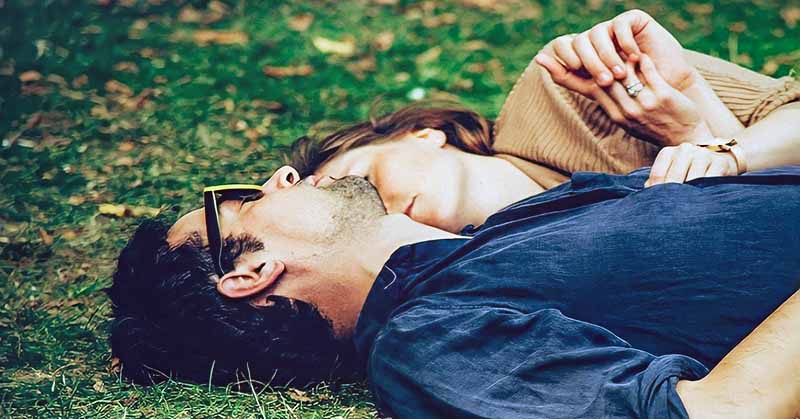 loved up couple in the honeymoon phase lying on grass