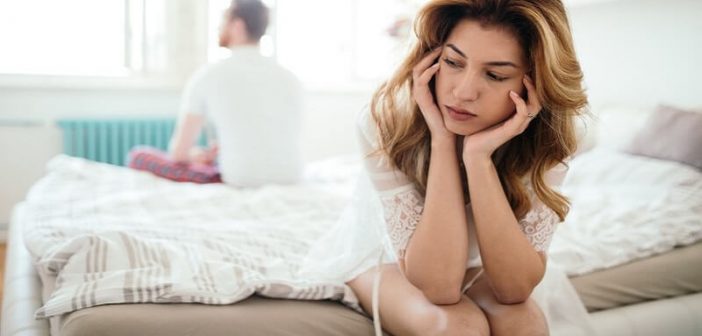 woman sitting on opposite side of bed to her partner indicating relationship difficulties