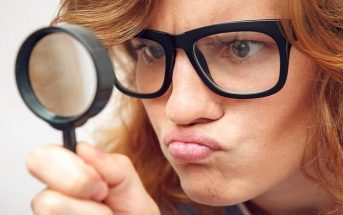 young woman looking through magnifying glass - illustrating being detail oriented