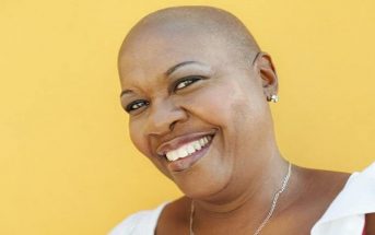 smiling black woman against yellow background - concept of a positive mental attitude