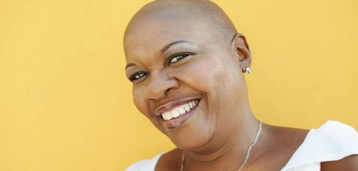 smiling black woman against yellow background - concept of a positive mental attitude