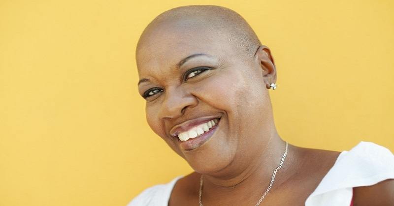 smiling black woman against yellow background - concept of a positive mental attitude