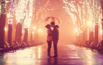 couple kissing under umbrella down a boulevard with lights