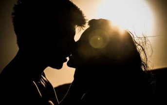 silhouette of young couple kissing against the sun - illustrating relationship myths